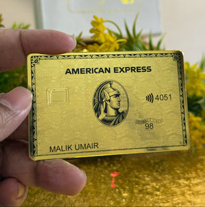 24k Gold American Express card held by a hand with a blurred background