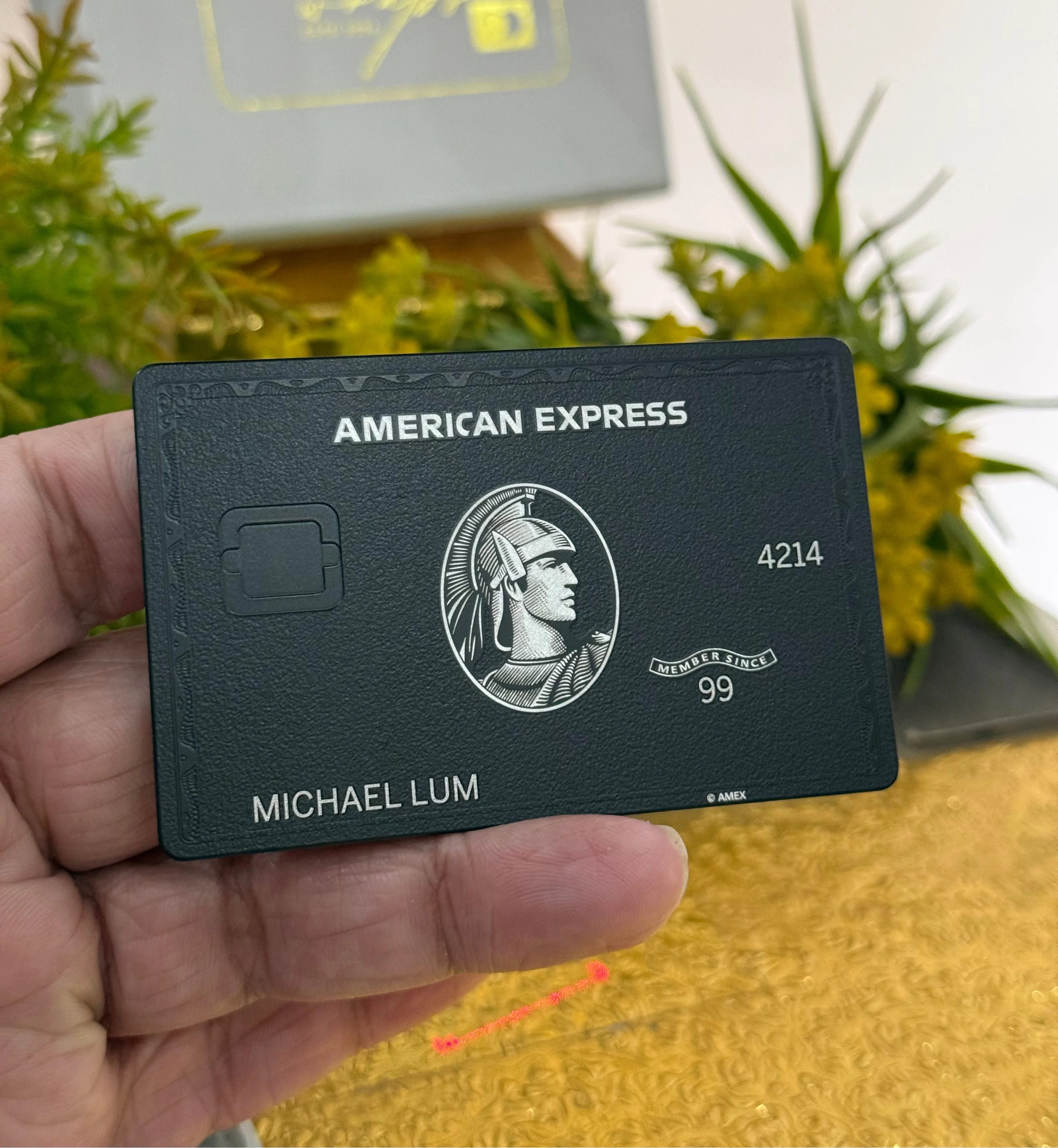 Hand holding an American Express black card with a blurred background