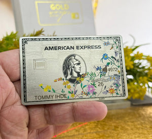 American Express Floral platinum card with leafs held by a hand with a blurred background